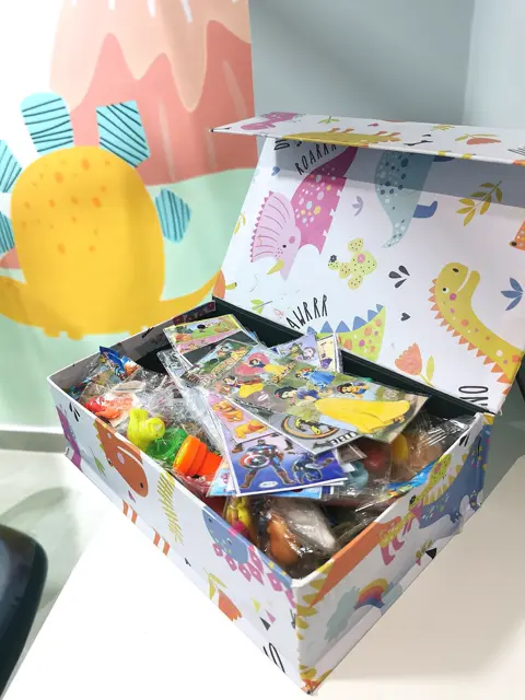 A caixa mágica aberta, cheia de brinquedos e presentes.